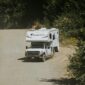A truck driving down a dirt road with an rv on it