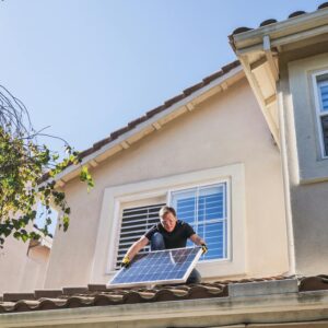Man in Blue Shirt and Black Pants Sitting on Roof